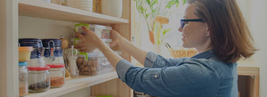 Banner for Blog page showing a woman organizing storage boxes on a kitchen shelf