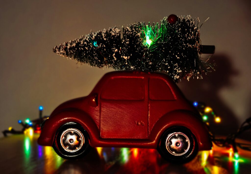 Miniature Volkswagen car carrying a miniature Christmas tree.