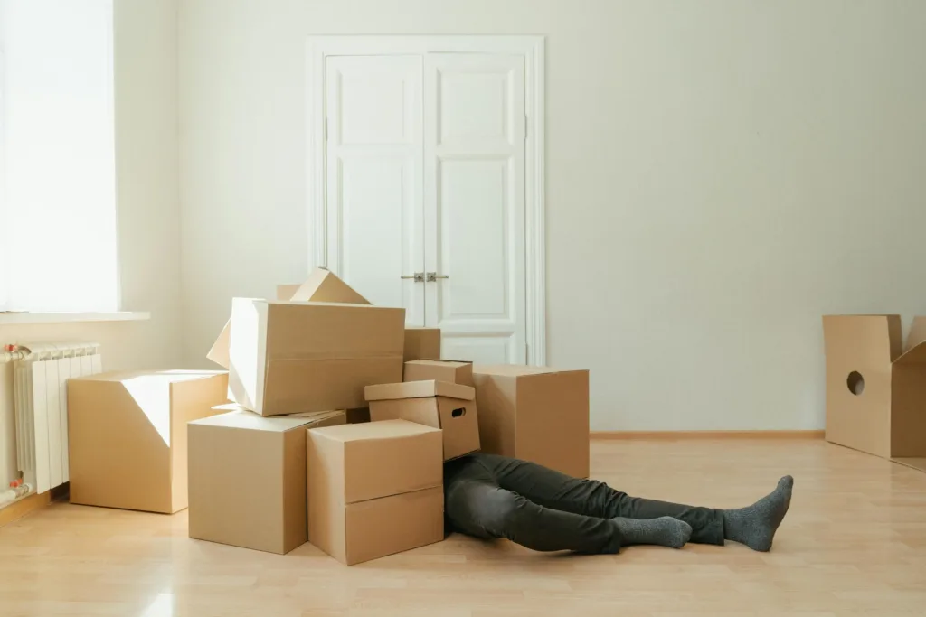 The Essential Steps to a Successful Move: A Step-by-Step Guide 1 person lying under a pile of empty cardboard boxes. Illustration for blog post: steps to a successful move