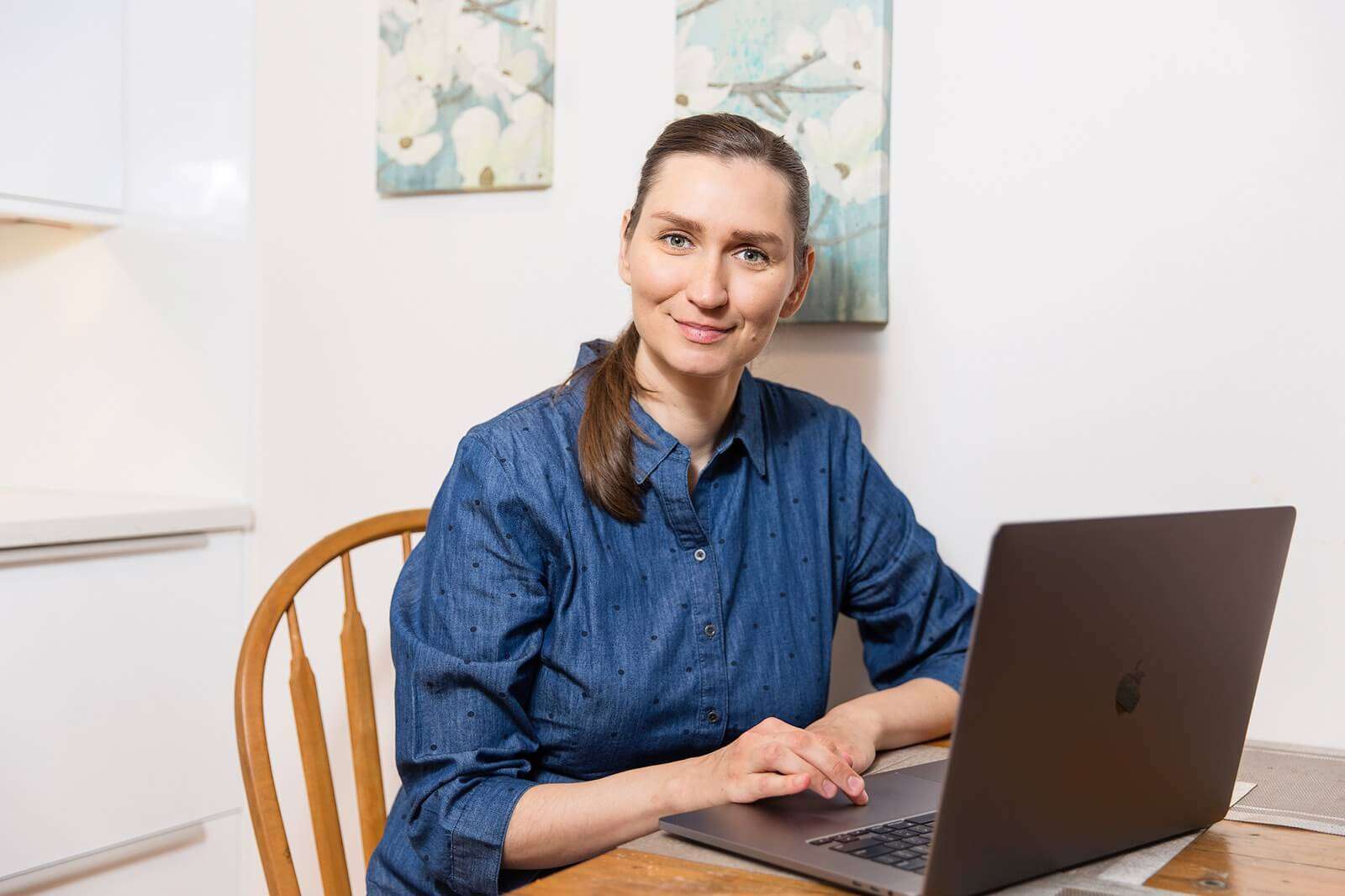 Olena from Harmony Home Organizing sitting at a table in front of a laptop as illustration for Virtual Organizing Services