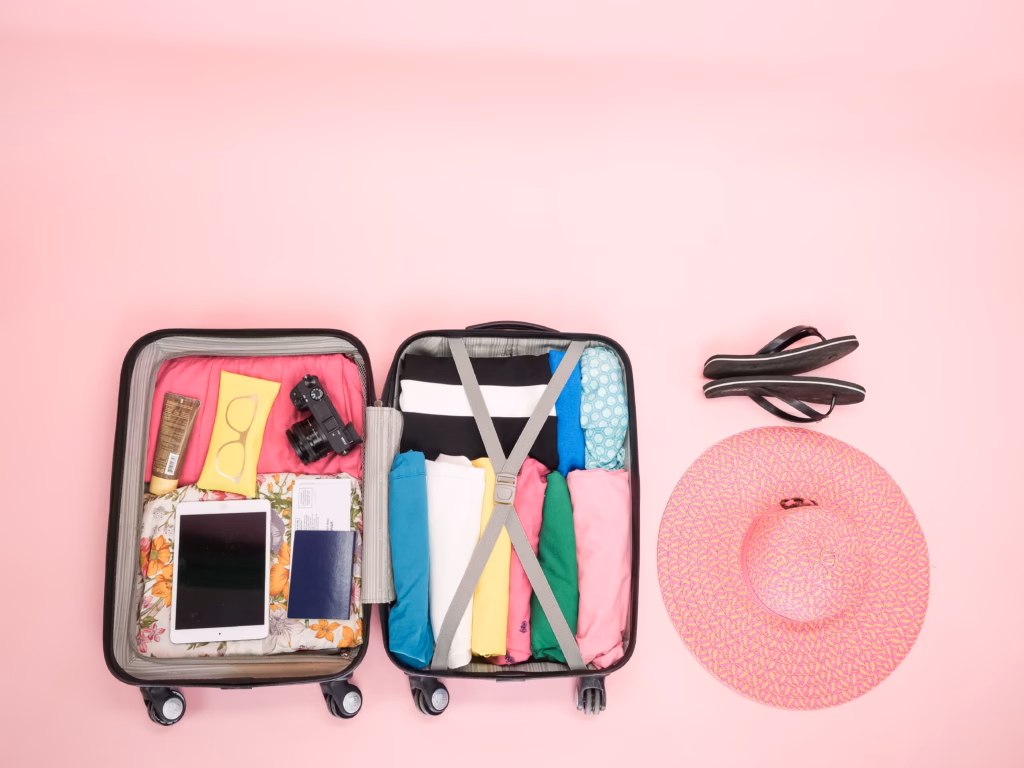 How to Stay Organized During Summer Holidays and Travel 1 Packed open suitcase on pink background Illustration for blog about travel organization tips.